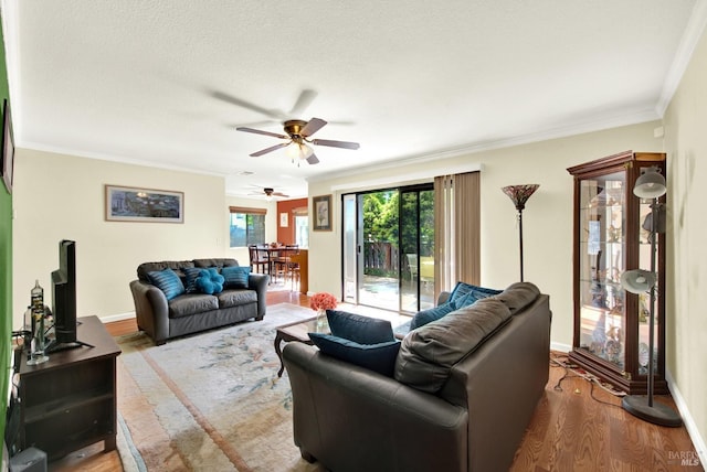 living area with crown molding, a ceiling fan, and wood finished floors