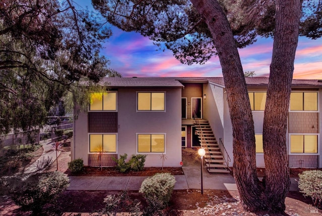 view of front of house featuring fence, stairs, and stucco siding
