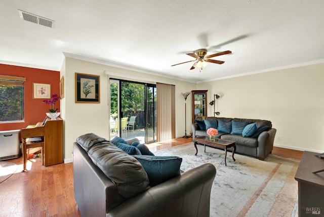 living area with ceiling fan, ornamental molding, light wood-style flooring, and visible vents