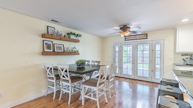 dining area with visible vents, baseboards, light wood finished floors, french doors, and a ceiling fan