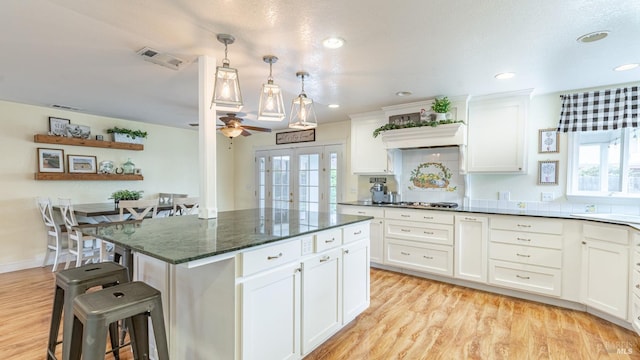 kitchen featuring white cabinetry, visible vents, and a kitchen bar