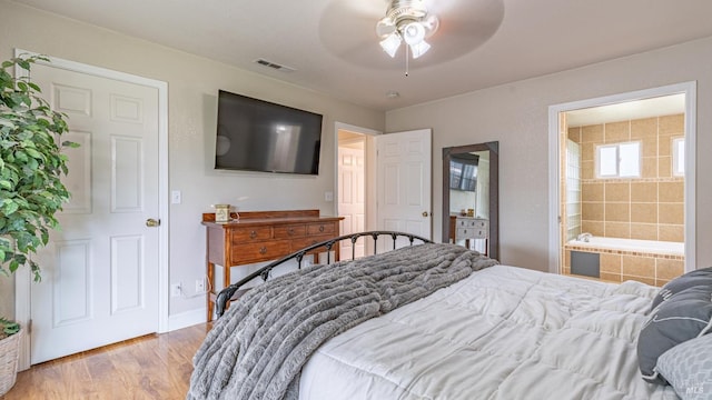 bedroom featuring light wood finished floors, a ceiling fan, visible vents, baseboards, and ensuite bathroom