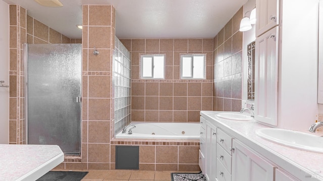 bathroom featuring tile patterned flooring, a jetted tub, a sink, and a shower stall