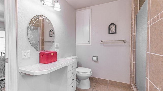 bathroom featuring a shower with shower door, vanity, toilet, and tile patterned flooring