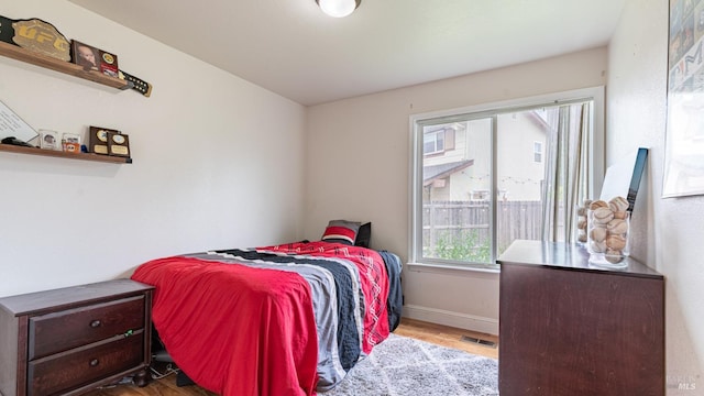 bedroom with baseboards, visible vents, and wood finished floors