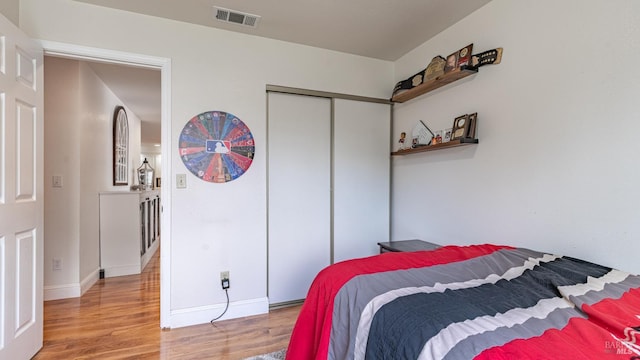 bedroom with baseboards, visible vents, a closet, and light wood-style flooring
