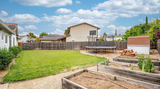 view of yard with an outdoor structure, a trampoline, a storage unit, a vegetable garden, and a fenced backyard