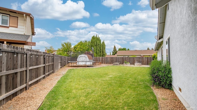 view of yard featuring a storage unit, a fenced backyard, and an outdoor structure