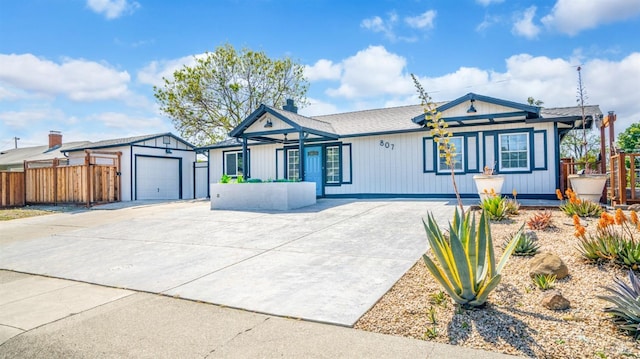 ranch-style home featuring fence, concrete driveway, an outbuilding, and a garage