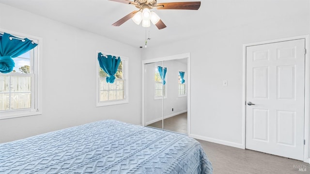 bedroom featuring ceiling fan, a closet, baseboards, and multiple windows
