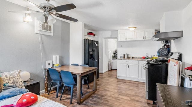 kitchen with ventilation hood, white cabinets, range with gas stovetop, and black fridge with ice dispenser
