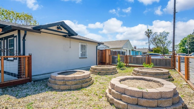 back of property featuring stucco siding, a fire pit, and a fenced backyard