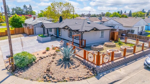 ranch-style home with driveway, a residential view, an outdoor fire pit, fence, and a garage