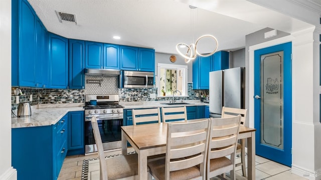 kitchen with a sink, appliances with stainless steel finishes, light tile patterned floors, tasteful backsplash, and blue cabinets
