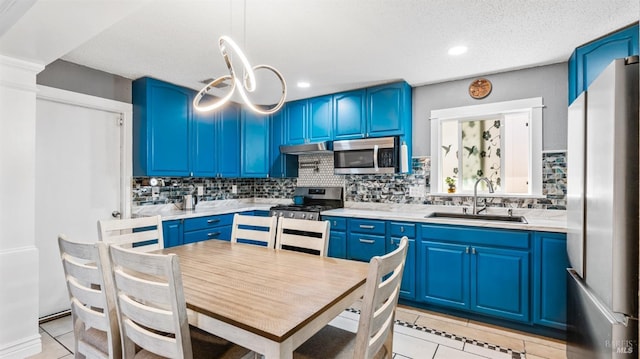 kitchen featuring a sink, blue cabinets, stainless steel appliances, and under cabinet range hood
