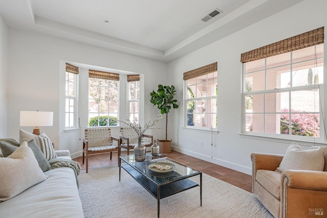 living area featuring baseboards, tile patterned flooring, a tray ceiling, and visible vents