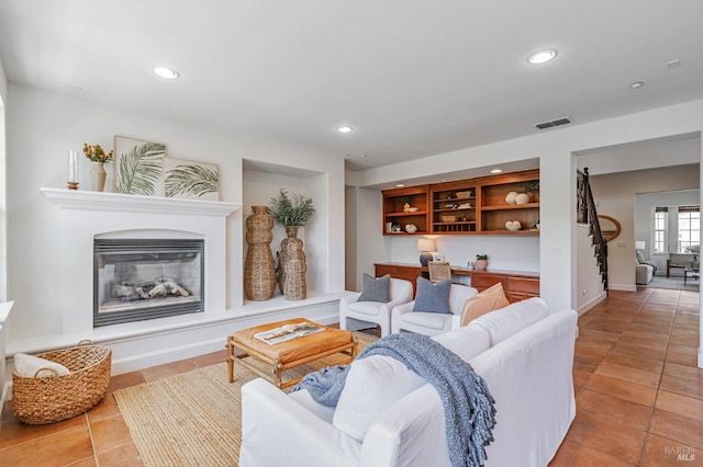 living area with light tile patterned floors, a glass covered fireplace, and recessed lighting