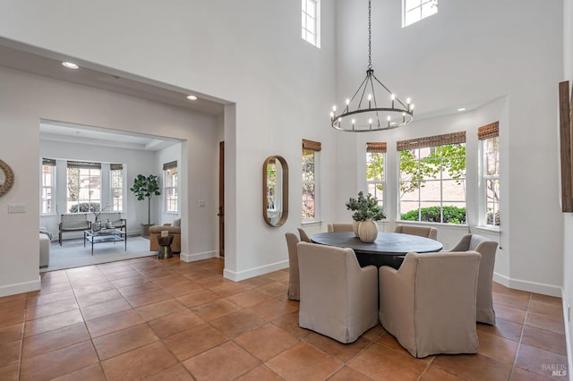 dining room featuring an inviting chandelier, baseboards, a high ceiling, and recessed lighting