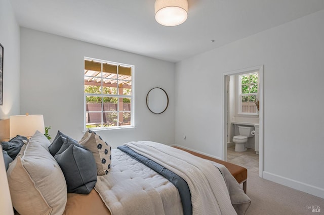 bedroom featuring carpet floors, baseboards, and ensuite bath