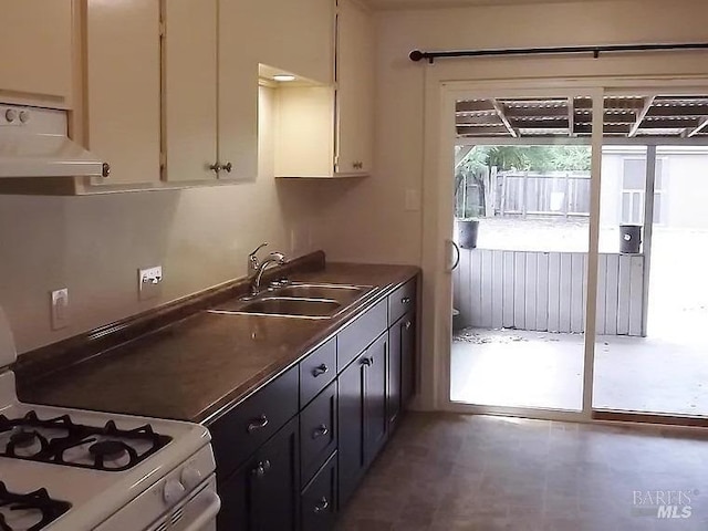 kitchen featuring white gas stove, white cabinets, extractor fan, and a sink