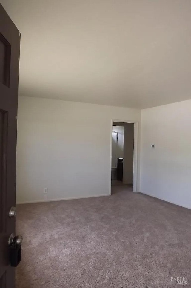 spare room featuring carpet and baseboards