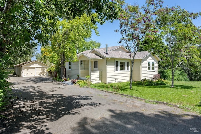 bungalow-style house with an outbuilding, a front yard, and a detached garage