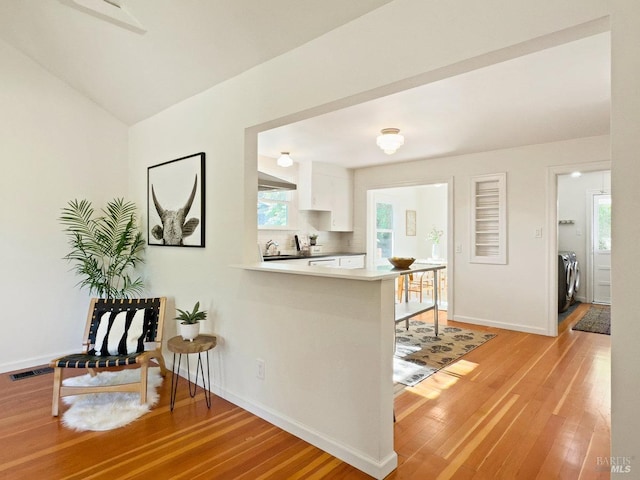 kitchen with separate washer and dryer, white cabinetry, light wood finished floors, and visible vents