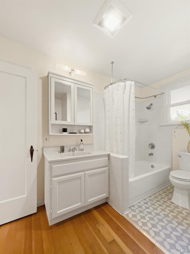 full bath with vanity, shower / tub combo with curtain, toilet, wood finished floors, and visible vents