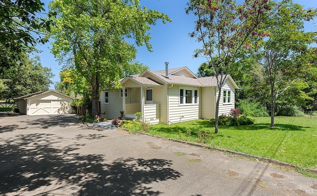 bungalow featuring a detached garage, an outbuilding, and a front lawn