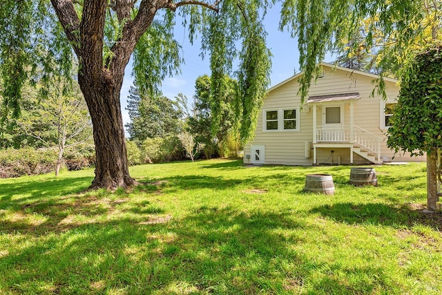 back of property with a lawn, cooling unit, and an outdoor fire pit