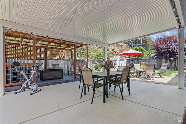 view of patio featuring an outdoor structure, outdoor dining area, a fenced backyard, and a shed