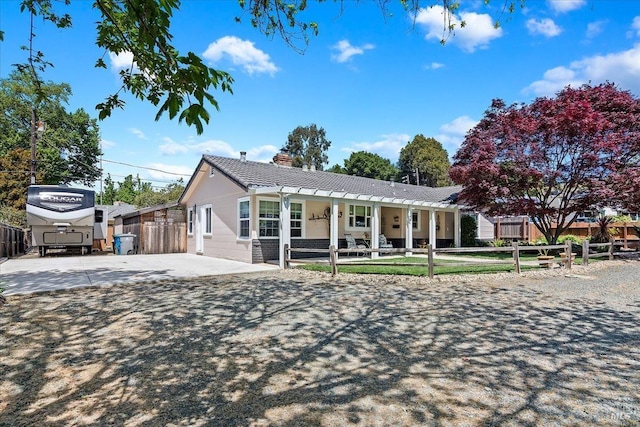 view of front facade with a chimney, concrete driveway, and fence private yard