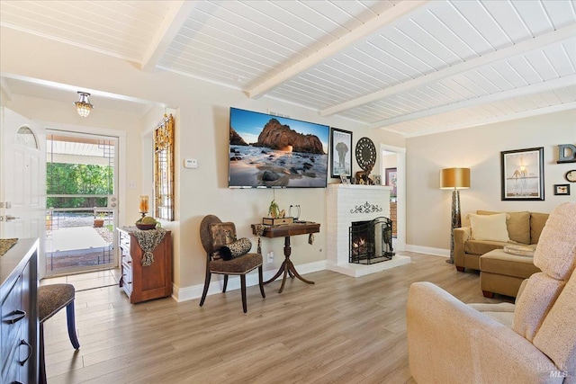 living room featuring a fireplace, light wood-type flooring, beam ceiling, wooden ceiling, and baseboards