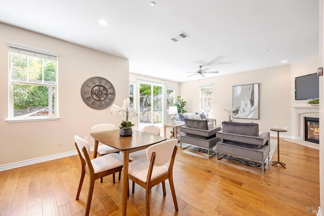 dining area with a wealth of natural light, light wood-style floors, a ceiling fan, and visible vents