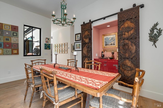 dining room with an inviting chandelier, light wood-style flooring, a barn door, and baseboards