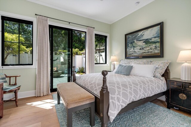 bedroom with ornamental molding, access to exterior, multiple windows, and wood finished floors