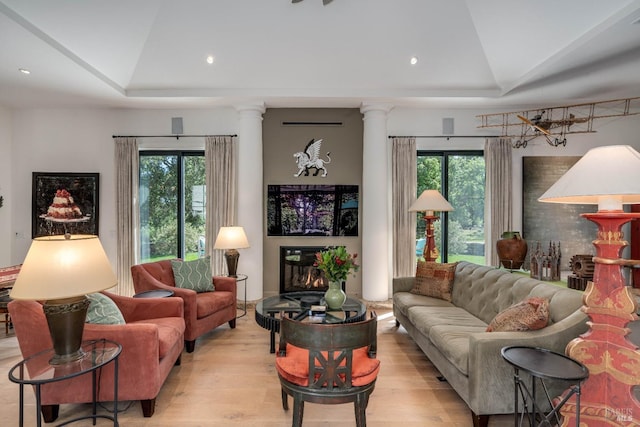 living area with recessed lighting, a tray ceiling, light wood-style floors, and ornate columns