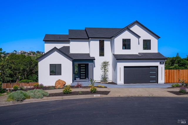 modern farmhouse with driveway, stucco siding, roof with shingles, an attached garage, and fence