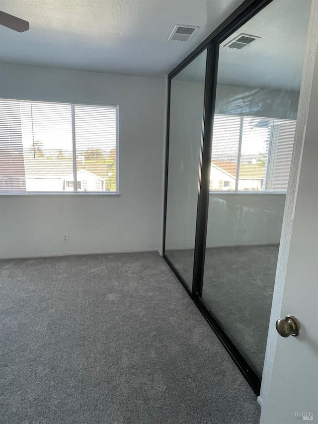 unfurnished bedroom with visible vents, carpet floors, and multiple windows