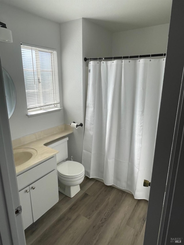 bathroom with wood finished floors, toilet, a shower with curtain, and vanity
