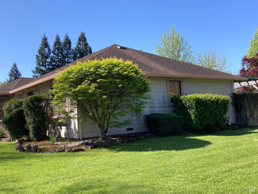 view of side of home featuring a lawn and roof with shingles