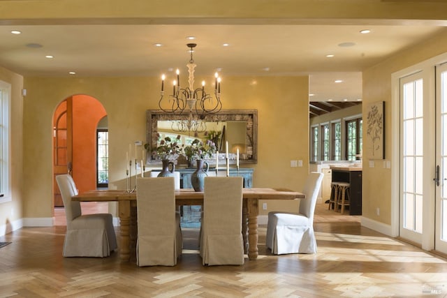 dining room featuring an inviting chandelier, arched walkways, baseboards, and recessed lighting