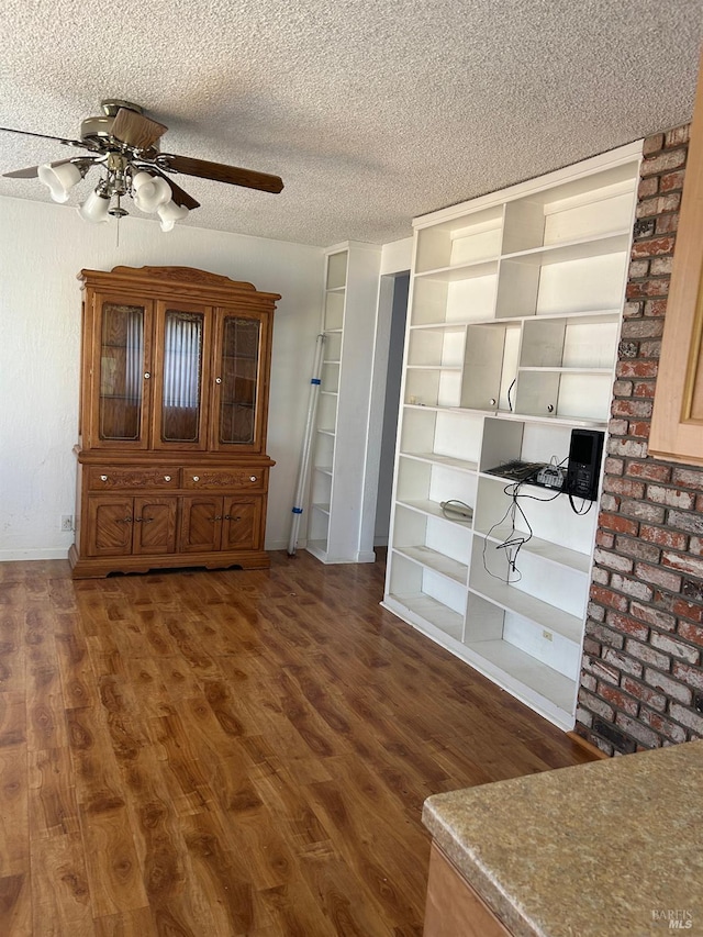 unfurnished dining area with wood finished floors, a ceiling fan, and a textured ceiling