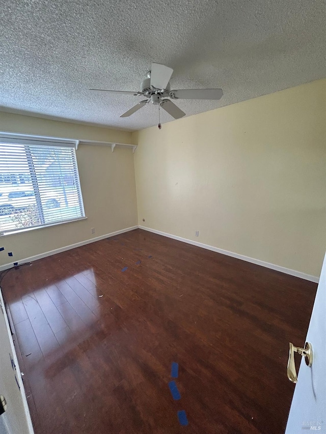 spare room featuring baseboards, wood finished floors, ceiling fan, and a textured ceiling