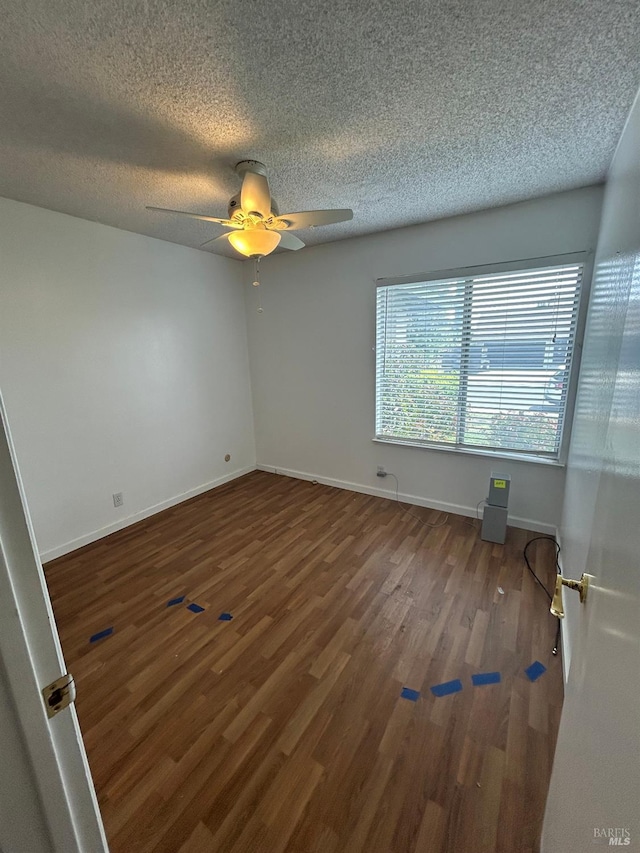 unfurnished room with a textured ceiling, wood finished floors, a ceiling fan, and baseboards