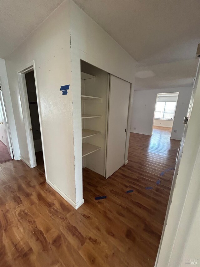 hallway featuring wood finished floors and baseboards