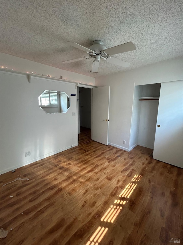 unfurnished bedroom featuring baseboards, wood finished floors, a ceiling fan, and a textured ceiling