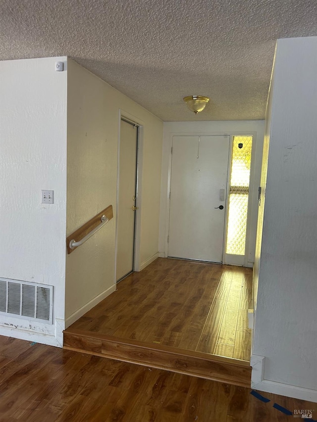 entryway featuring wood finished floors, visible vents, baseboards, and a textured ceiling