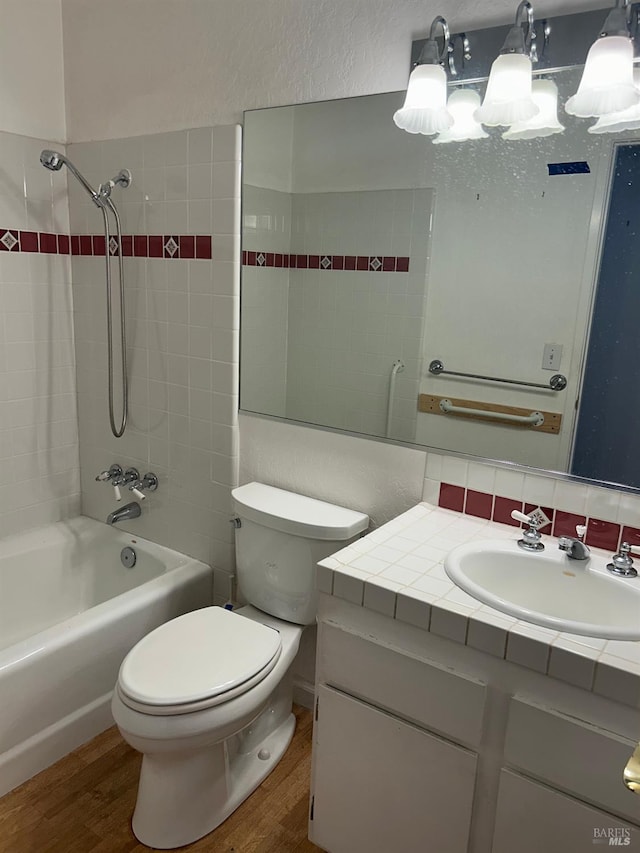 bathroom with toilet, vanity, tub / shower combination, and wood finished floors