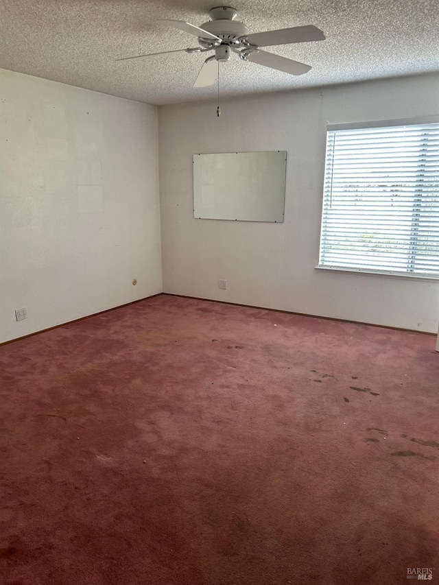 carpeted empty room featuring a ceiling fan and a textured ceiling